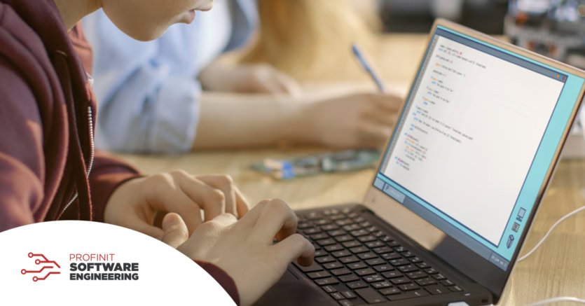 A child types code on a laptop, while another takes notes in the background. The Profinit Software Engineering logo in the corner.
