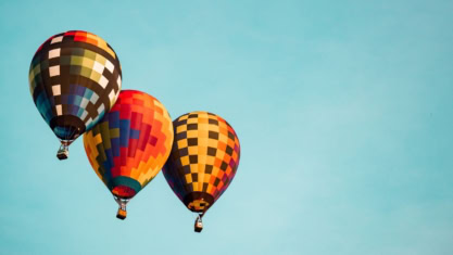 Three colorful hot air balloons with checkered patterns float —like an architecture of 3A Systems.