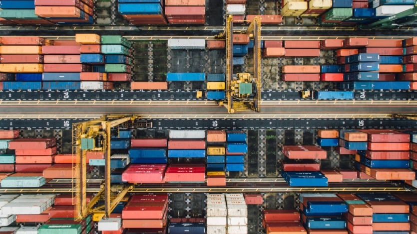 Aerial view of a shipping container yard with cranes and rows of containers, illustrating organized data in Data warehouse.