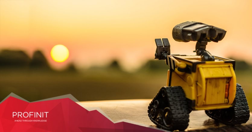 A small robot on tracks looks toward a sunset ,blending human intuition with big data. PROFINIT logo.