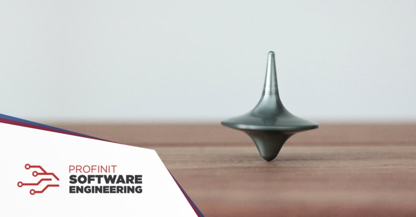 A spinning metal top on a wooden surface captures the balance of focus and efficiency at work, with a Profinit logo in the corner.